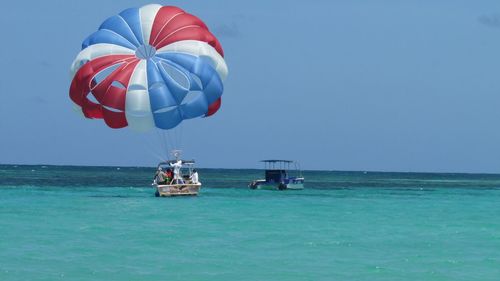 People parasailing on sea against clear sky