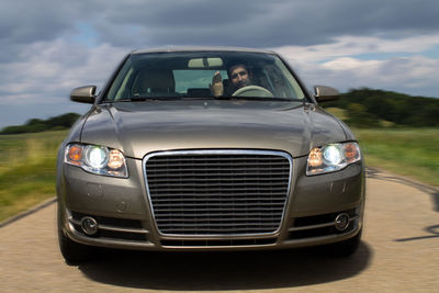 Angry man gesturing in car seen through windshield against cloudy sky