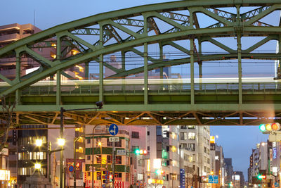 Low angle view of illuminated bridge against buildings