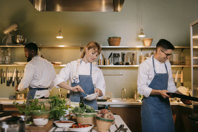 Multiracial male and female chef preparing food in commercial kitchen
