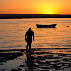 Silhouette of people in water at sunset