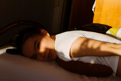 Close-up portrait of young woman relaxing on bed at home