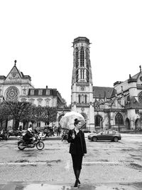 Full length of woman with umbrella while standing in city