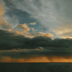 Scenic view of sea against cloudy sky at sunset