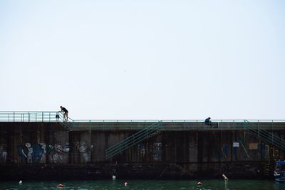 People on bridge against clear sky