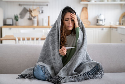 Young woman sitting on sofa at home