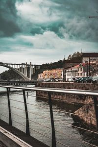 Bridge over river against cloudy sky