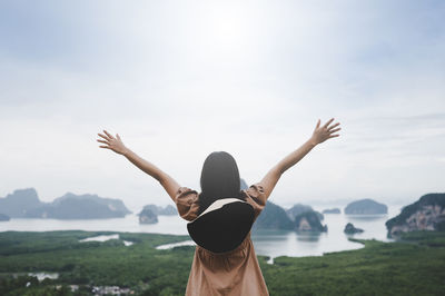 Rear view of woman standing by mountain against sky