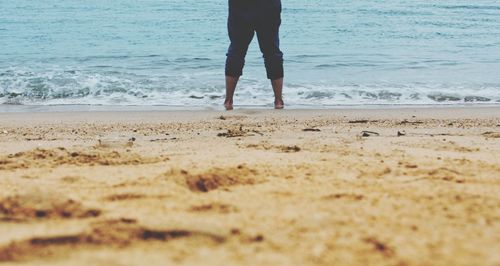 Low section of man standing on beach