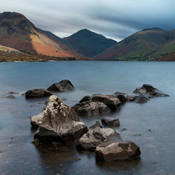 Rocks in sea against mountains