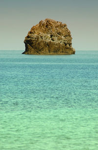 Scenic view of rocks in sea against clear sky