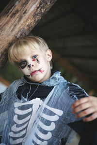 Portrait of a boy in halloween costume standing against tree