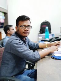 Portrait of young man sitting at desk in office