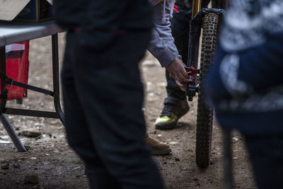 Low section of men repairing bicycle outdoors