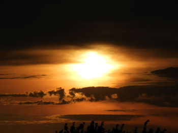 Scenic view of dramatic sky over silhouette landscape during sunset