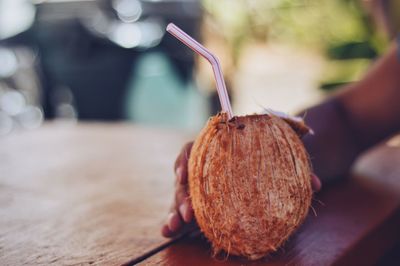 Cropped image of hand holding coconut at table