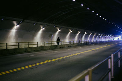 Man on illuminated road in stockton tunnel