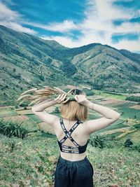 Woman standing on field by mountain against sky