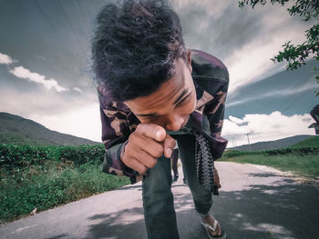 Full length of man holding umbrella on road against sky