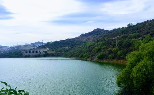 Scenic view of river by mountains against sky