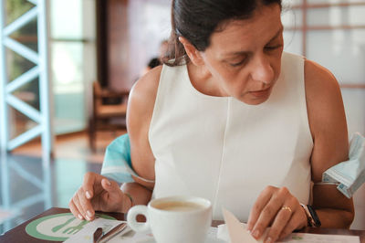 Woman sitting by coffee cup at restaurant