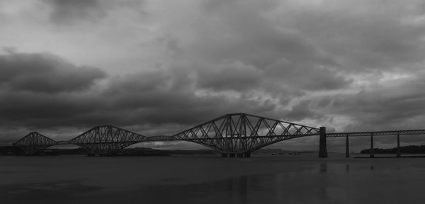 Bridge over river against cloudy sky