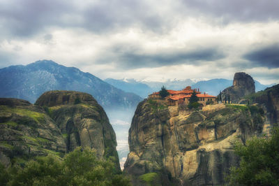 Low angle view of meteora against cloudy sky