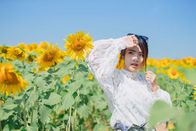 Low angle view of girl standing on sunflower field