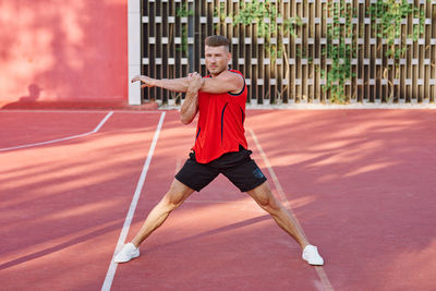 Full length of young woman exercising on court