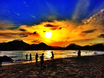 Silhouette of people on beach at sunset