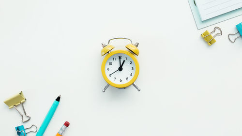 Paper clips, mechanical clock, pen, pencil and notepad on white background