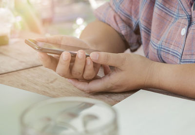 Close-up of man holding smart phone on table