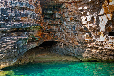 Layered stones structure of island vis. colored  geological layers and turquoise water of sea.