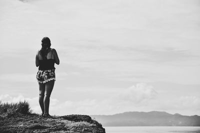 Rear view of woman standing on sea against sky