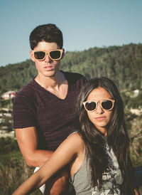 Young couple wearing sunglasses against sky