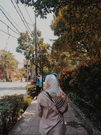 Rear view of woman with umbrella on street
