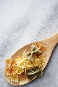 Close-up of farfalle in wooden spoon on marble