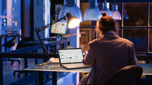 Rear view of woman using mobile phone in cafe