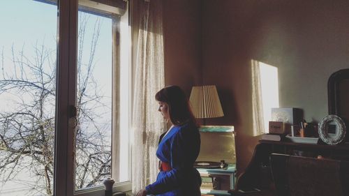 Woman standing by window at home