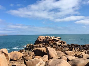 Scenic view of rocks on shore against sky