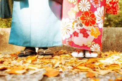 Low section of man standing by autumn leaves