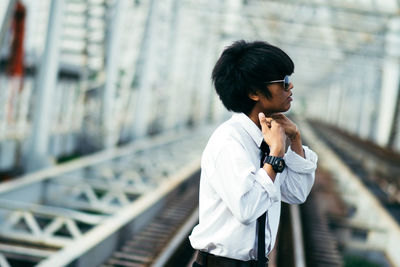 Side view of man standing at railway bridge