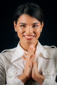 Portrait of a smiling young woman over black background