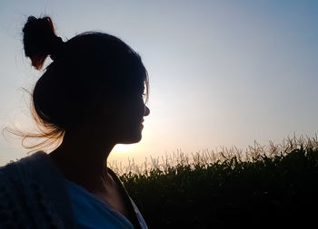 Silhouette woman in field against clear sky during sunset