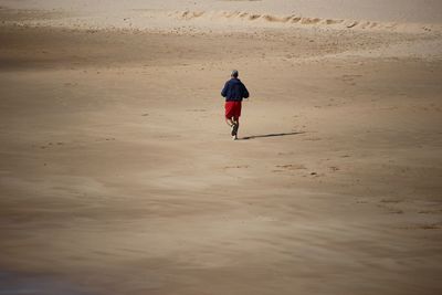 Rear view of man jogging on beach