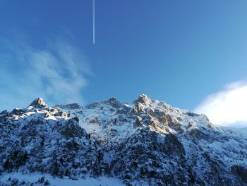 Low angle view of snowcapped mountains against blue sky