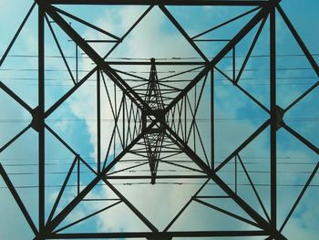 Low angle view of electricity pylon against blue sky