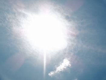 Low angle view of sunlight streaming through clouds