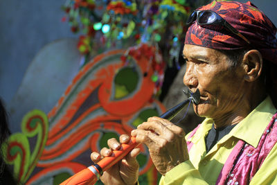 Close-up of mature woman playing musical instrument while standing outdoors