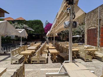 Chairs and tables by building against clear sky